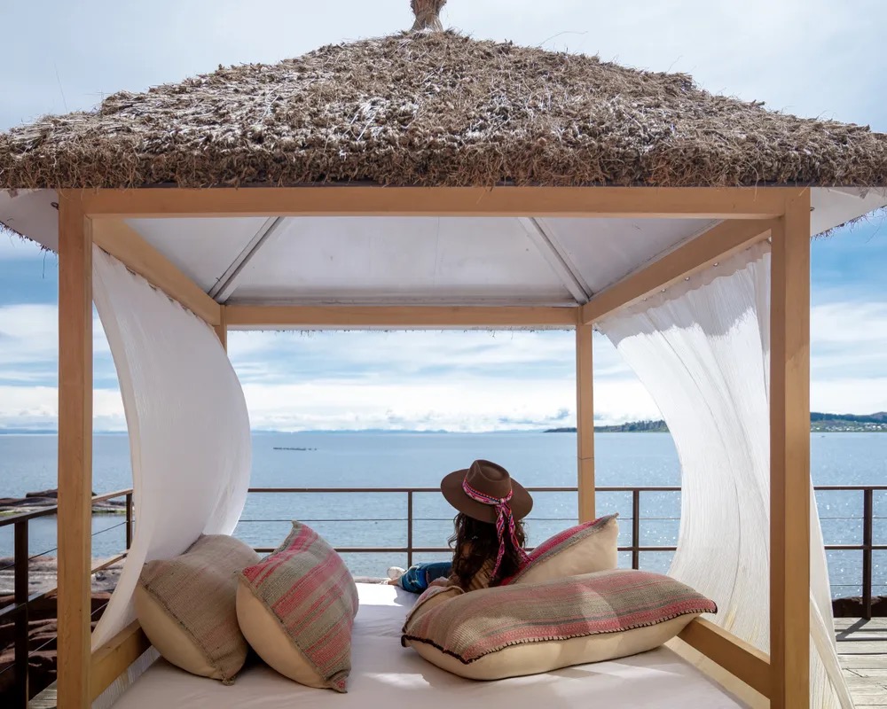 A thatched daybed pavilion on the shore at Titilaka
